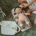 Child playing with a doll on a green carpet
