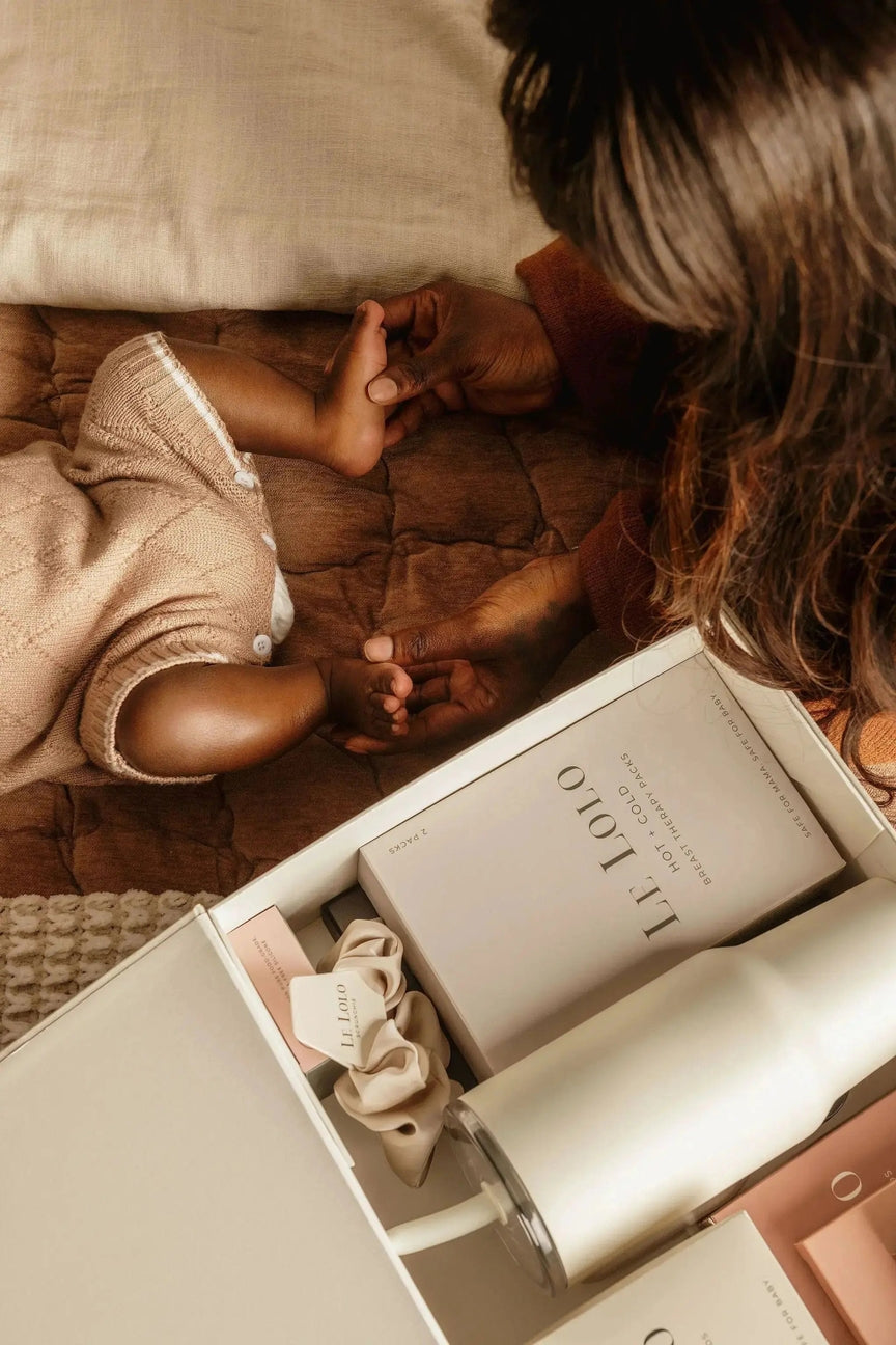 Child holding hands with an adult next to a box of L'OCCITANE products on a wooden floor.