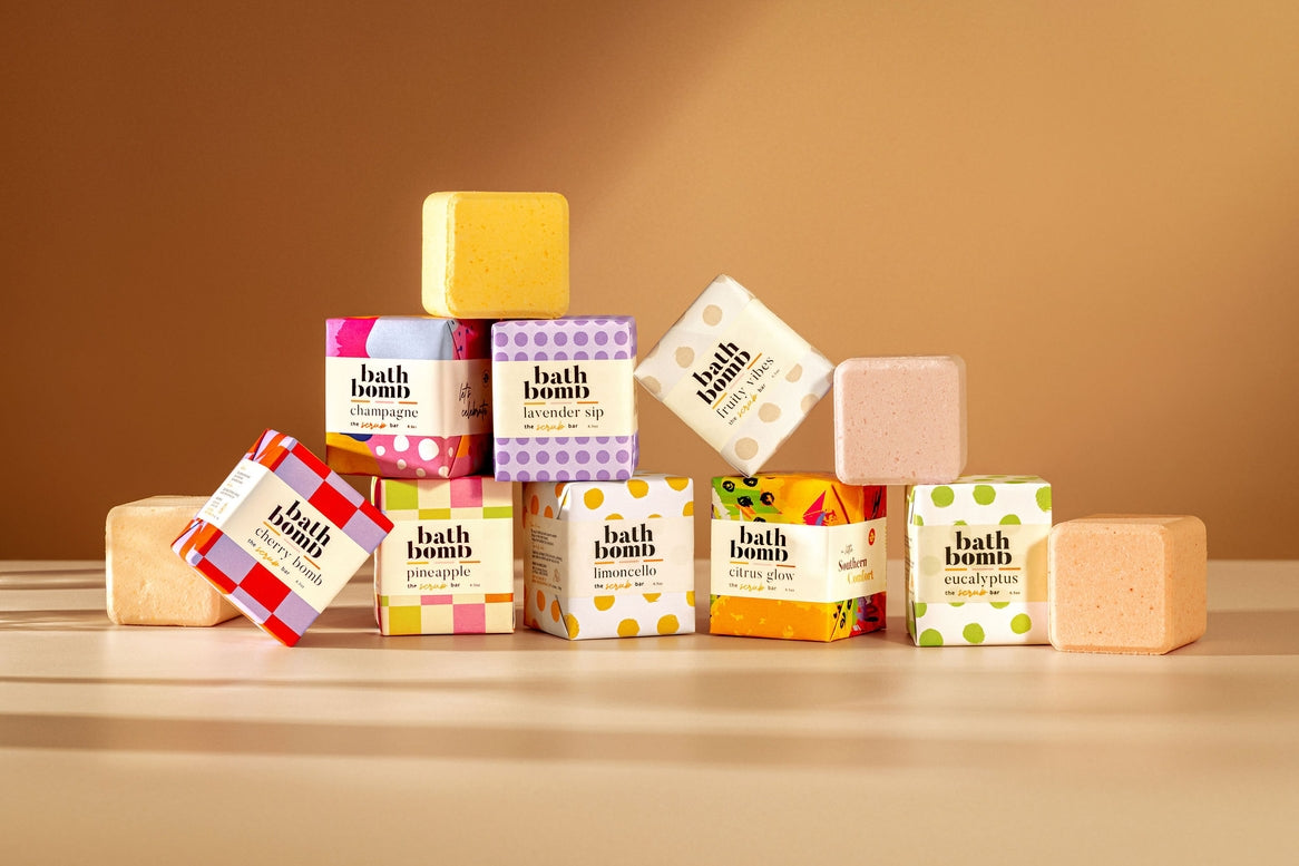 Collection of bath bombs with colorful packaging on a wooden surface against a brown background