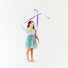 Young girl in a green dress holding a purple ribbon against a white background