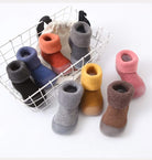 Colorful baby socks in a wire basket on a white background