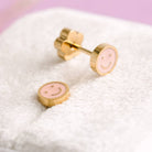 Pink smiley face earrings with gold accents on a white surface.