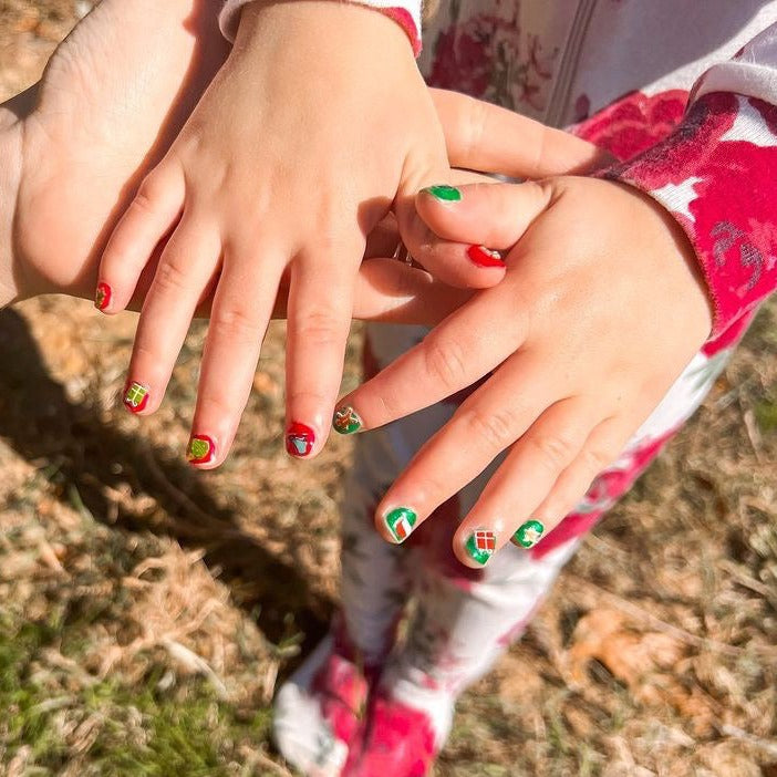 Close-up of two pairs of hands holding each other with colorful nail polish, outdoors.