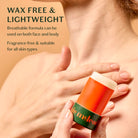 Hand holding a small container with text about wax-free and lightweight product on skin