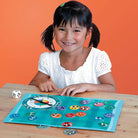 Young girl playing a board game with colorful game pieces on an orange background
