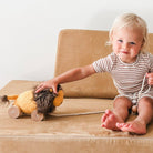 Child playing with a toy lion on a beige couch