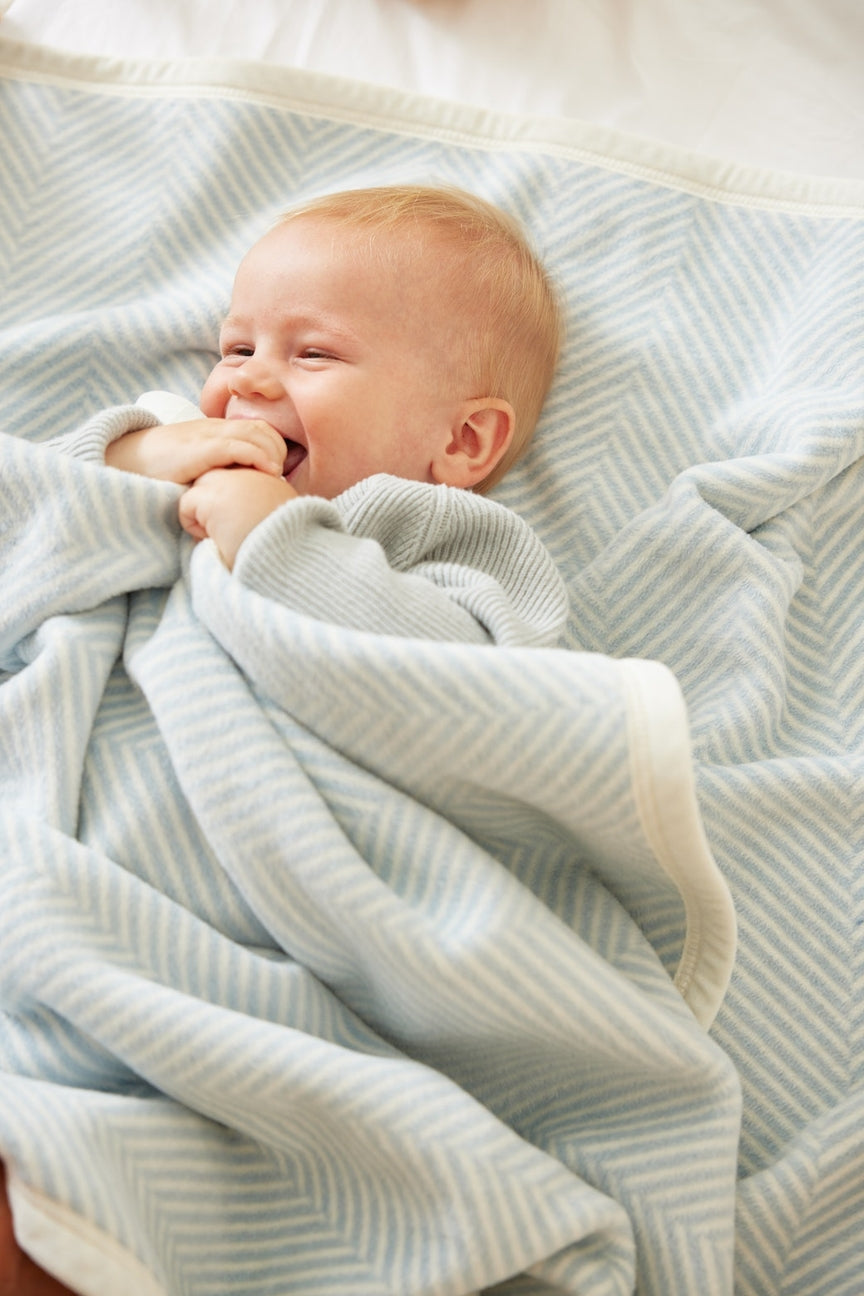 Baby's under a light blue blanket with a striped background