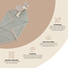 Baby blanket with toy on a beige background, featuring text about product features.