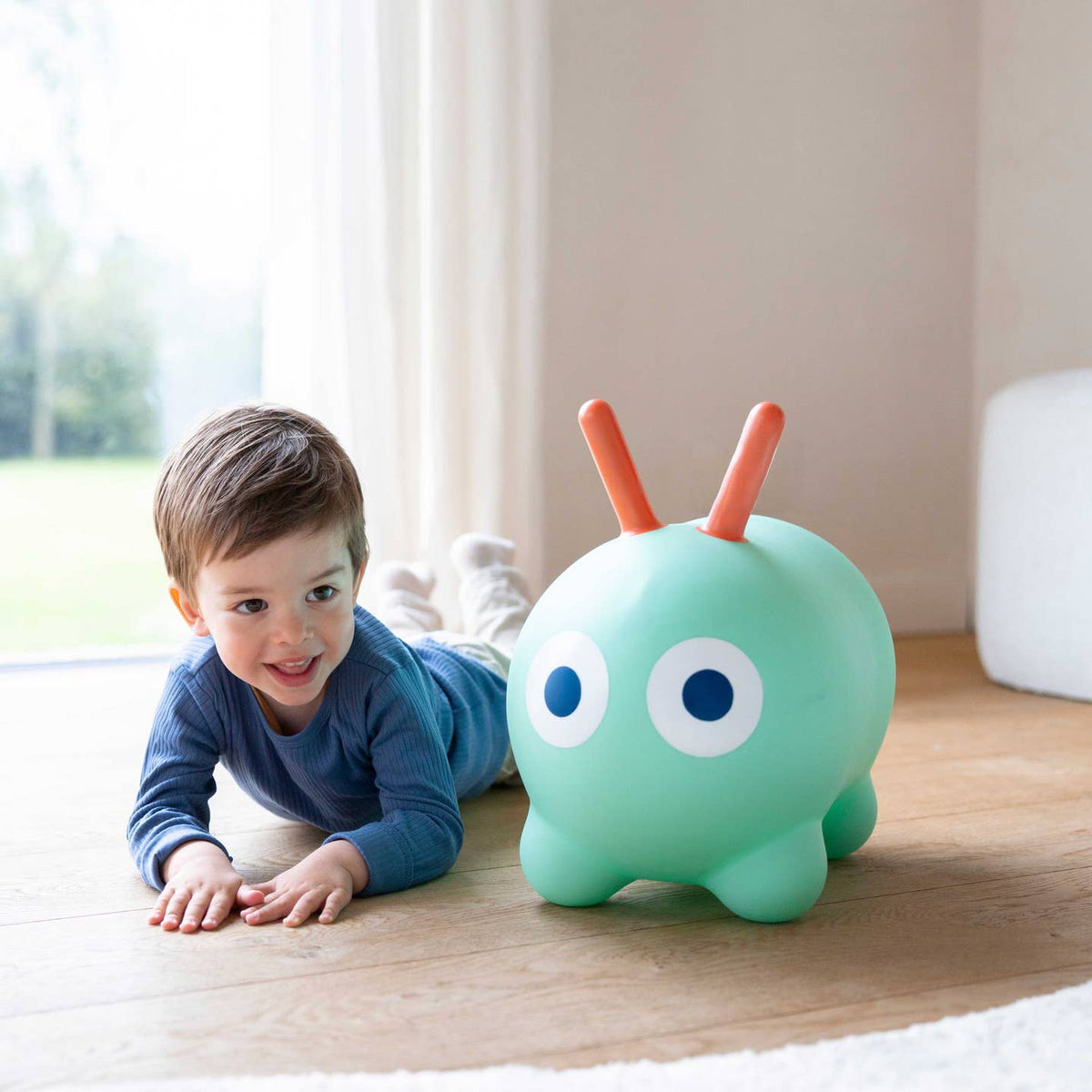 Child playing with a green toy on a wooden floor