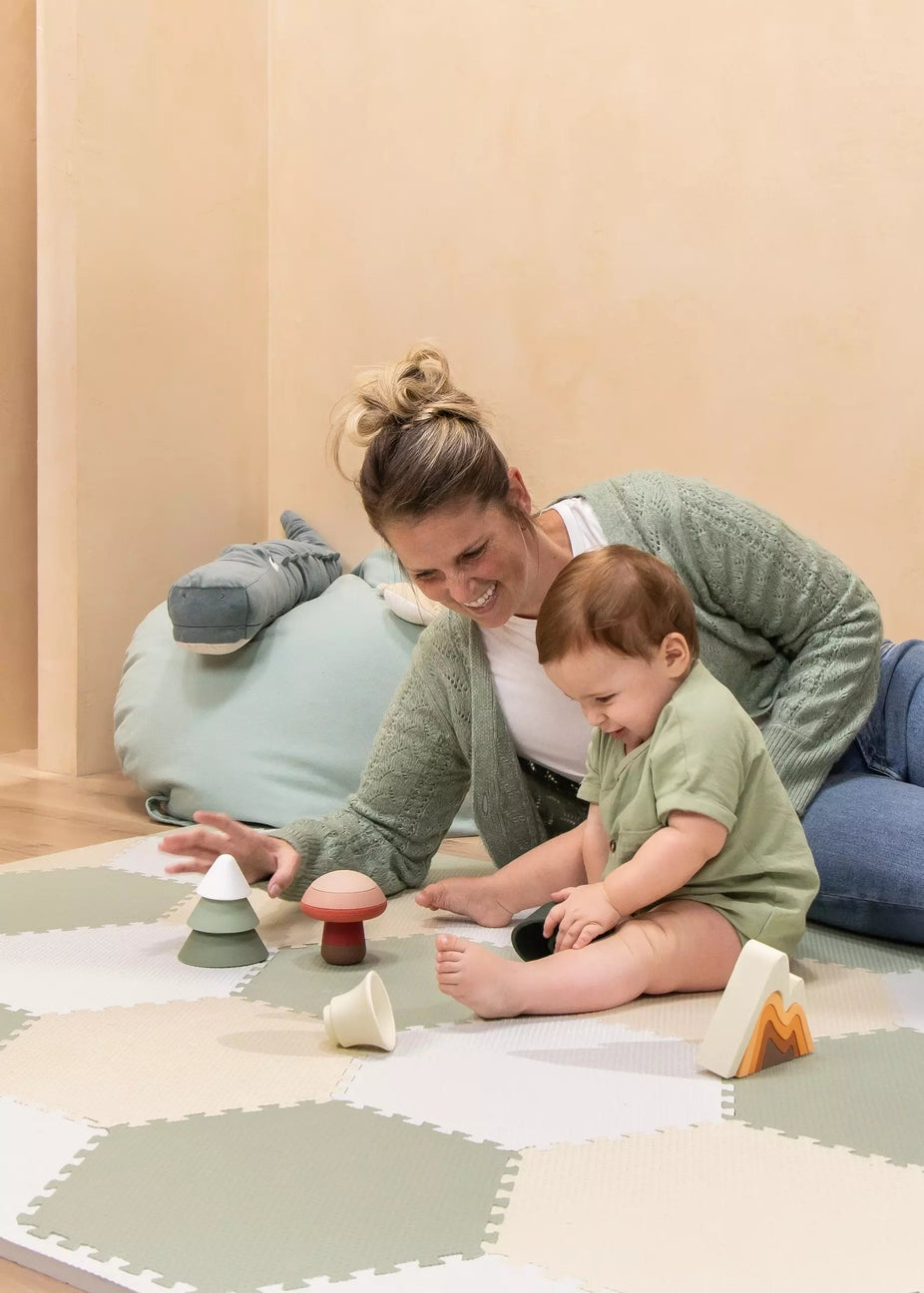 Woman and child playing with wooden toys on a soft play mat.