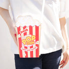Person holding a popcorn-themed pouch with a white background