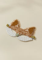 A plush fox-themed baby headband with patterned brown and white fabric ears, white padded cheeks, and small gold glitter accents, displayed on a light beige background.