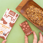 Almond Maple Brittle packaging with a wooden dish of brittle on a green background