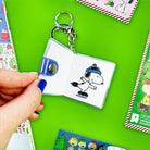 Keychain with a small book featuring a cartoon character on a green background