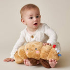 Baby holding a plush toy resembling a cartoonish bread character on a plain background