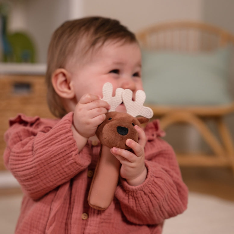 Child holding a plush toy with antlers indoors
