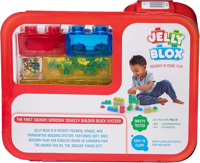 Product packaging for the Jelly Blox Creative Kit featuring a red carrying case with a clear window displaying colorful squishy building blocks, alongside an image of a child playing with the blocks and promotional text detailing product features.
