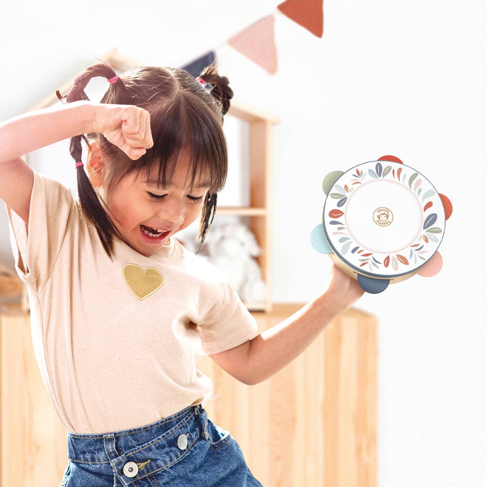 Child holding a colorful tambourine with a heart-shaped design on a light background