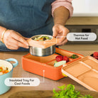 Person using a lunch box with a thermos for hot food and an insulated tray for cool foods.