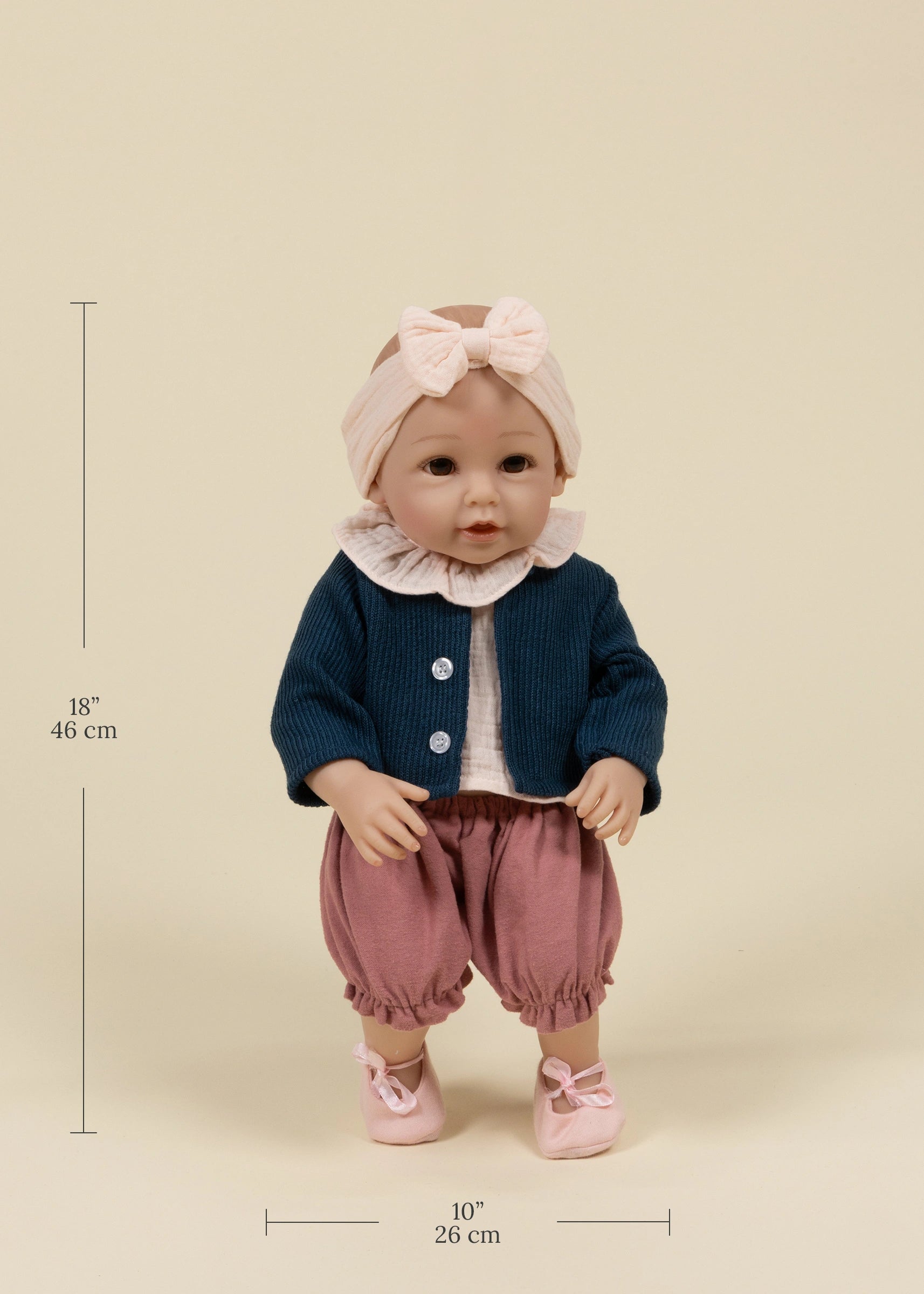 Baby doll in a outfit with measurements on a beige background