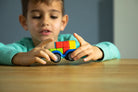 Child playing with a colorful toy car on a wooden table
