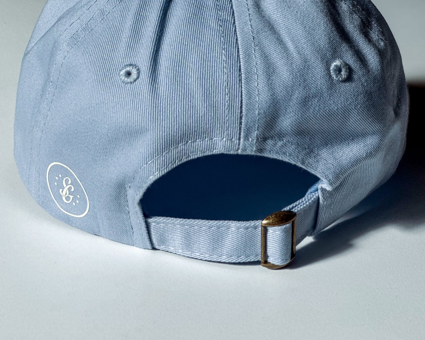 Light blue cap with a logo on the back against a light background