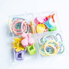 Colorful hair ties and clips in a clear plastic case on a white background