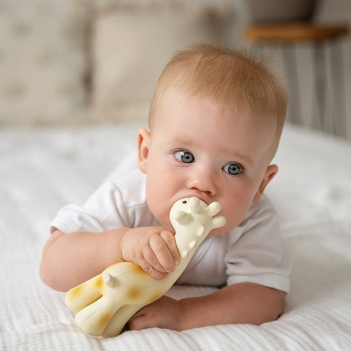 Baby holding a giraffe-shaped toy on a bed