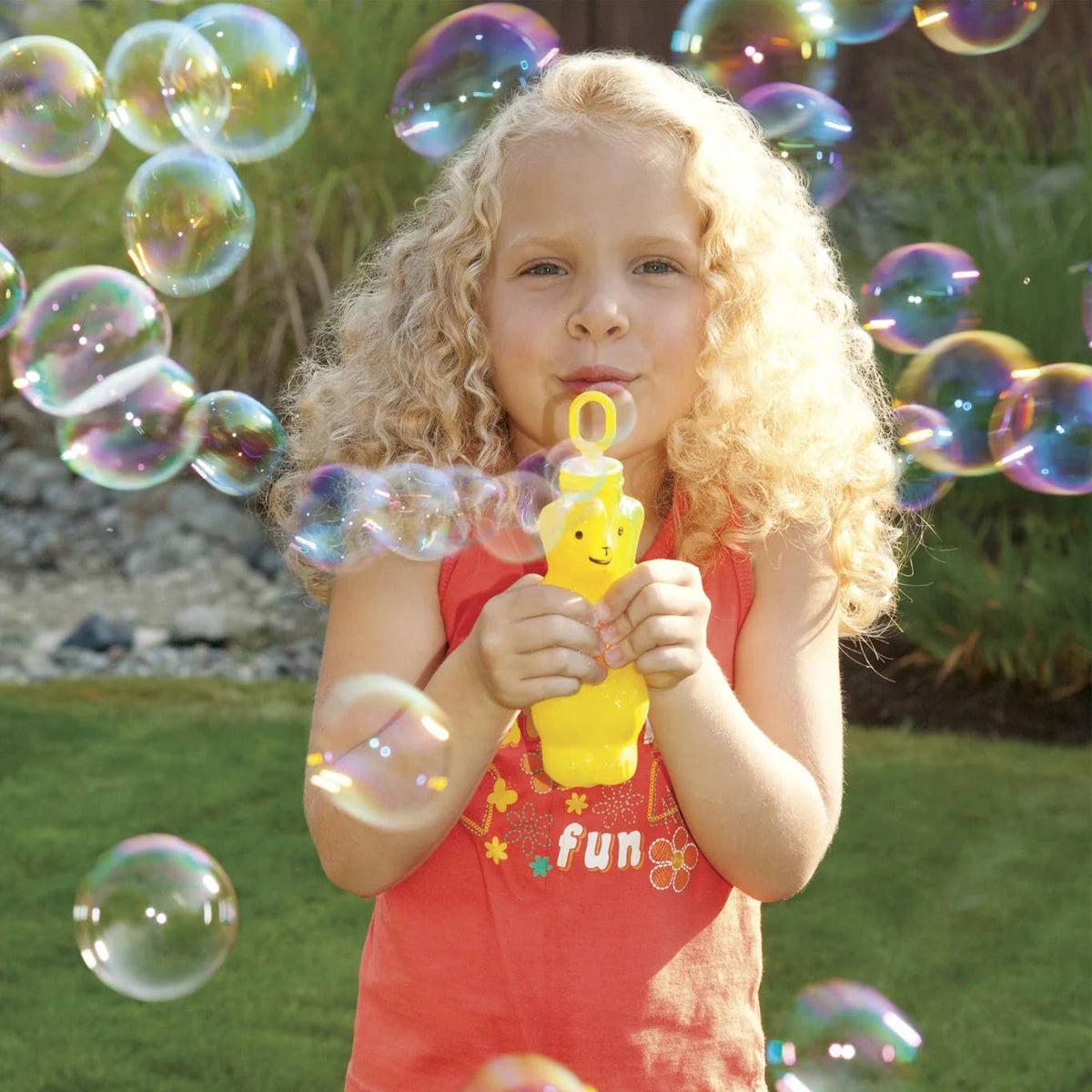 Young girl blowing bubbles outdoors with a bubble wand.