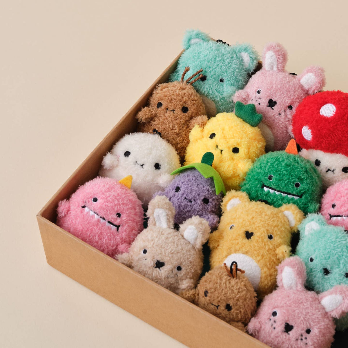 Box of colorful plush toys on a beige background