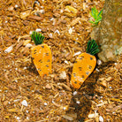 Carrot-shaped earrings on a mulched surface