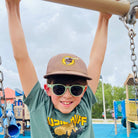 Child wearing sunglasses and a cap on a playground