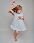 Young girl in a light blue dress jumping on a plain background