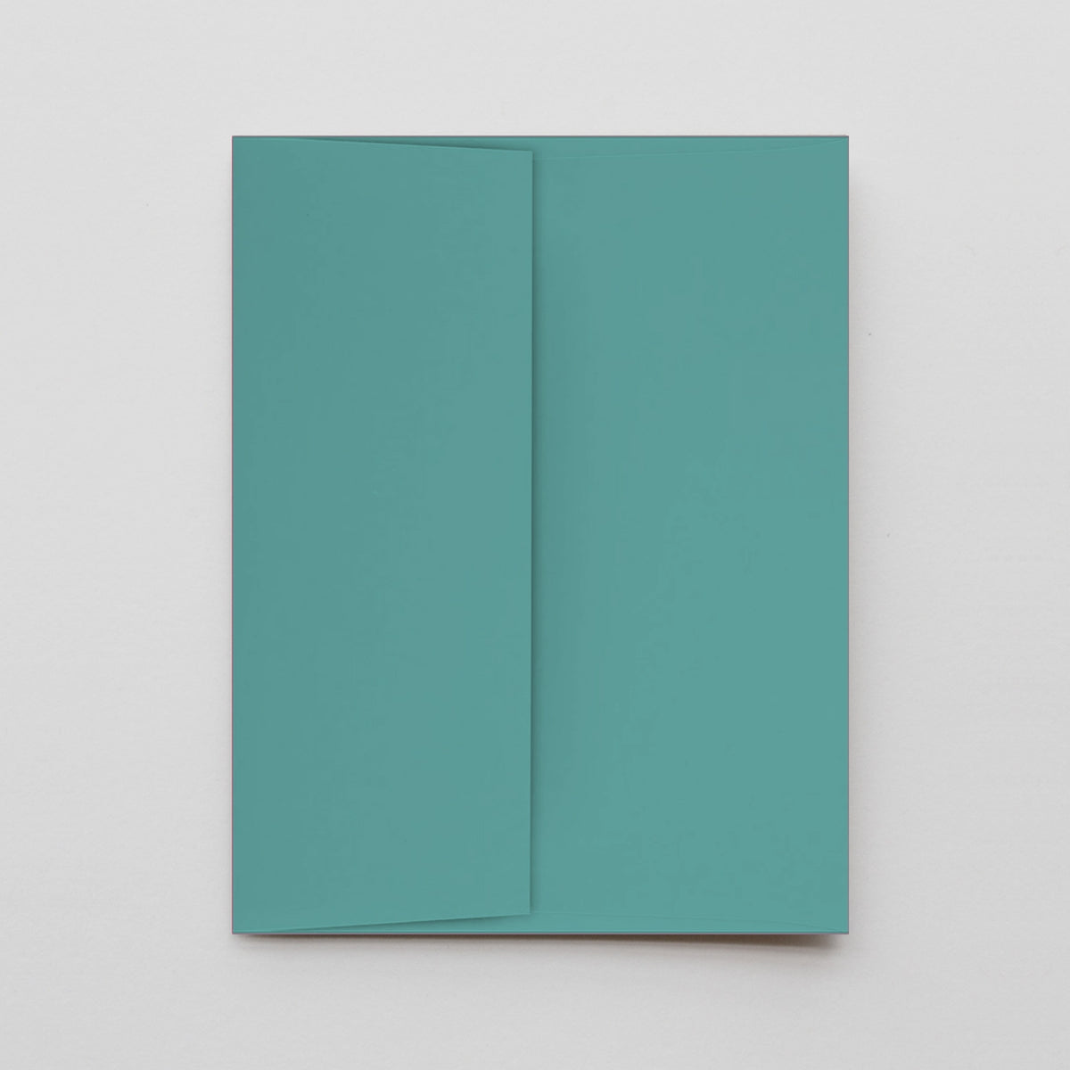 A minimalist teal notebook or journal with a matching envelope, shown flat-laid on a light gray background.