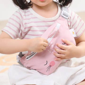 Child holding a pink backpack with cartoon design