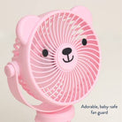 A pink bear-shaped portable fan with a cute face on the front grille, shown against a light beige background with the text 'Adorable, baby-safe fan guard' in the lower right corner.