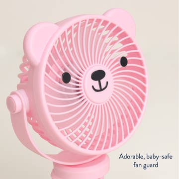 A pink bear-shaped portable fan with a cute face on the front grille, shown against a light beige background with the text 'Adorable, baby-safe fan guard' in the lower right corner.