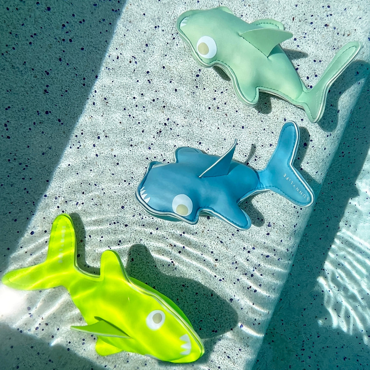 Three colorful shark-shaped objects on a textured surface