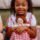 Child holding a doll wearing a red and white checkered dress