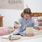 Young girl playing with woven baskets on a carpeted floor.