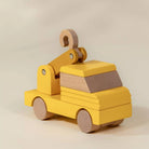 Wooden toy truck with yellow body and brown accents on a beige background