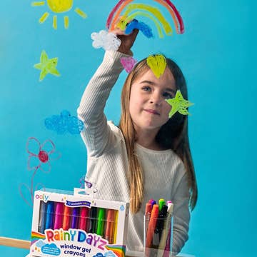 Child with colorful window gel crayons and craft items against a blue background