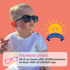 A baby wearing dark polarized sunglasses from Roshambo Eyewear featuring UV400 protection