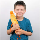 Child holding a plush carrot toy against a plain background
