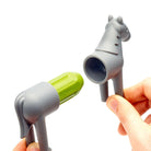 Gray and green kitchen tool shaped like a horse held by a hand on a white background