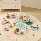 Collection of baby toys on a round rug in a room with wooden floor and white dresser.