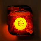 Packaged solar glow product with glowing yellow center on a dark background