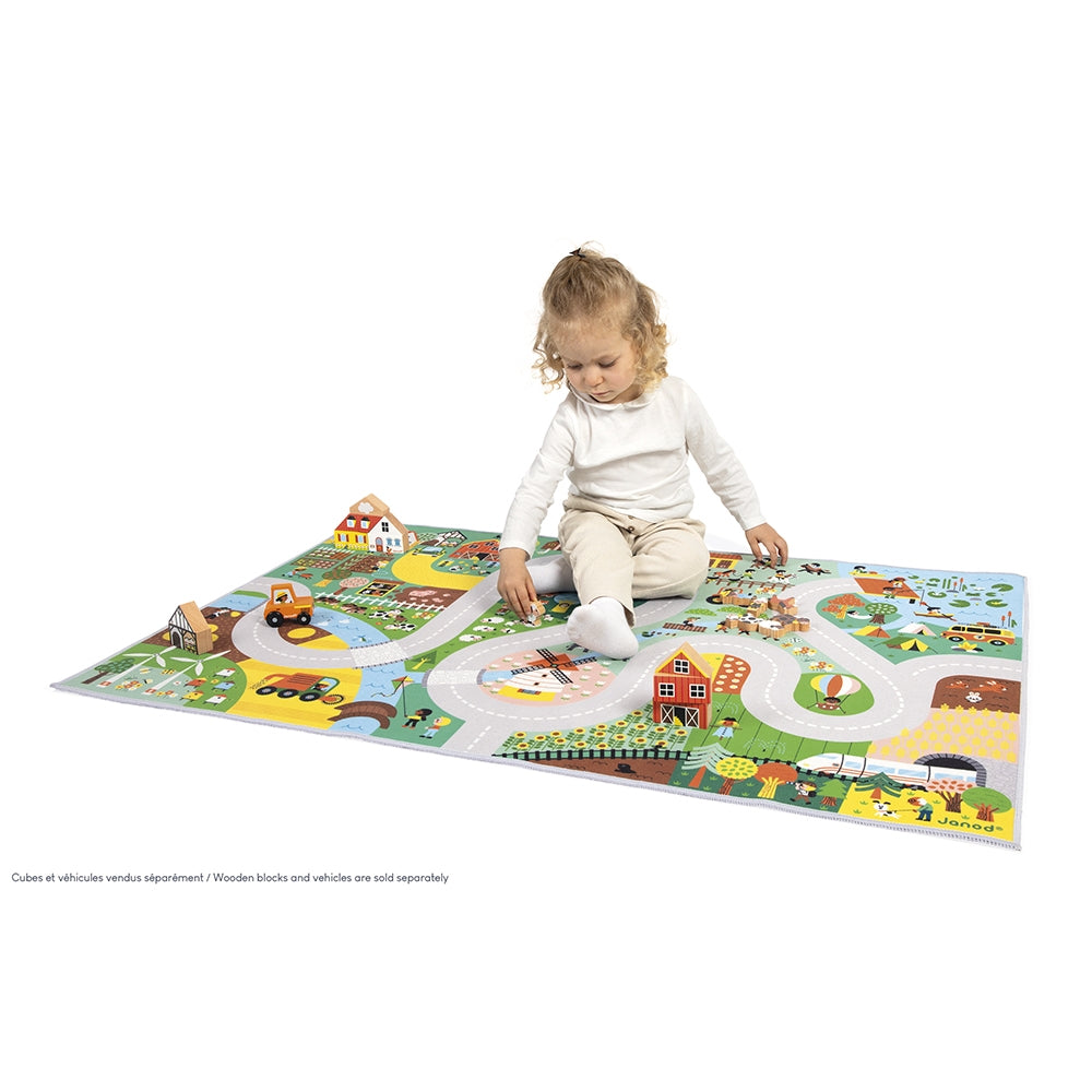 Child playing on a colorful play mat with vehicles and landscapes