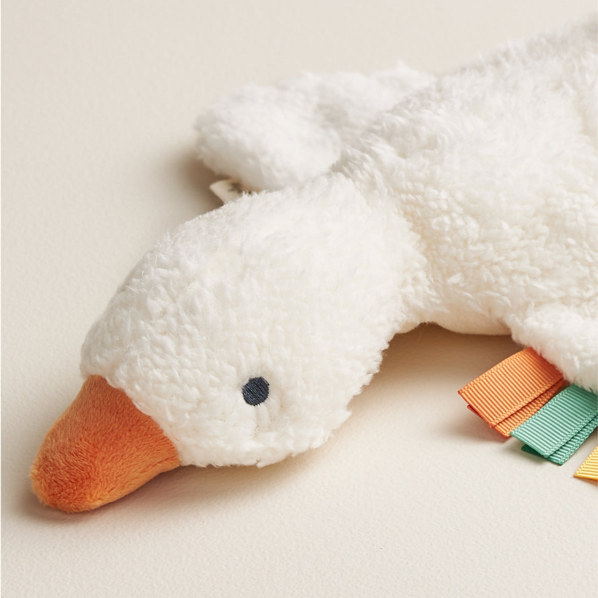 Plush toy duck with an orange beak on a light background