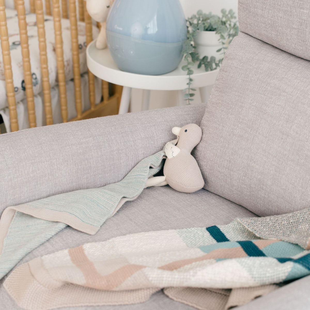 Gray sofa with a plush toy and baby blanket in a nursery setting
